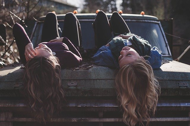 girls lying on a car