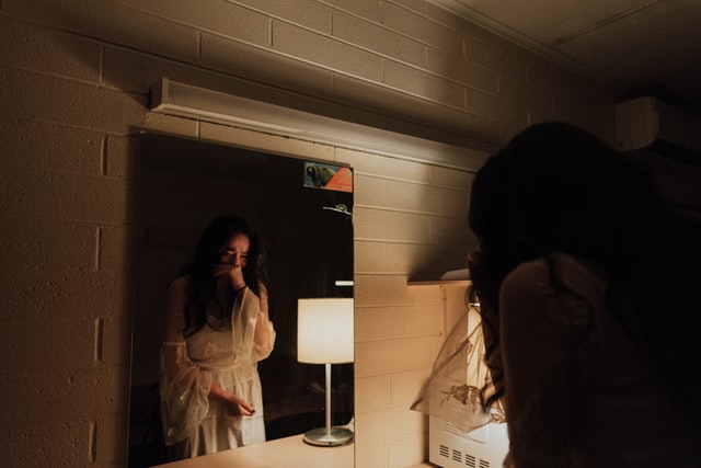 woman crying facing the mirror