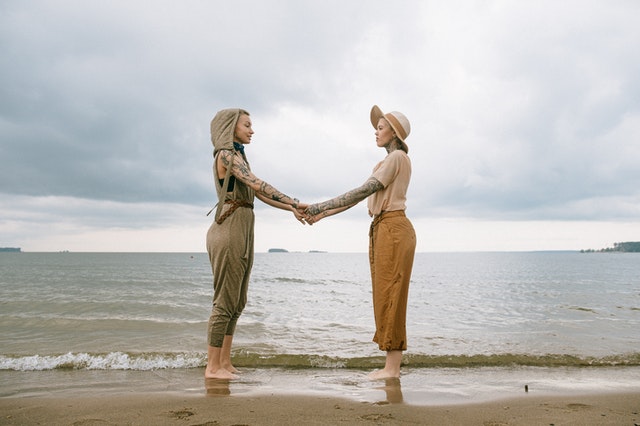 women holding hands at the beach