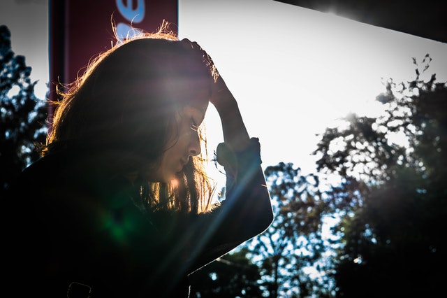 woman looking while holding head with left hand