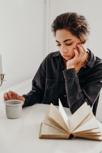 a sad woman looking on a ceramic cup of coffee