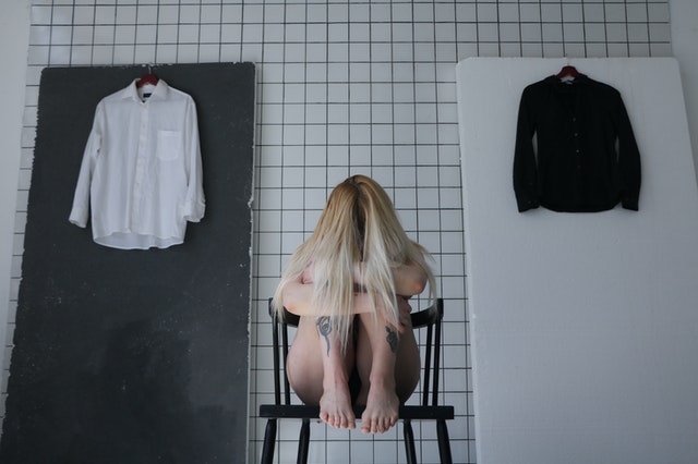 anonymous frustrated woman sitting on chair behind tiled wall