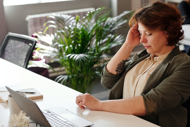 a corporate woman holding her head