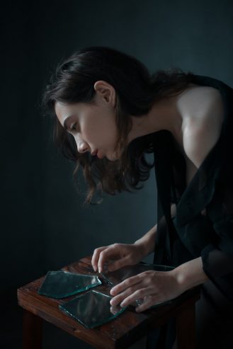 melancholic ethnic woman with-broken mirror at home
