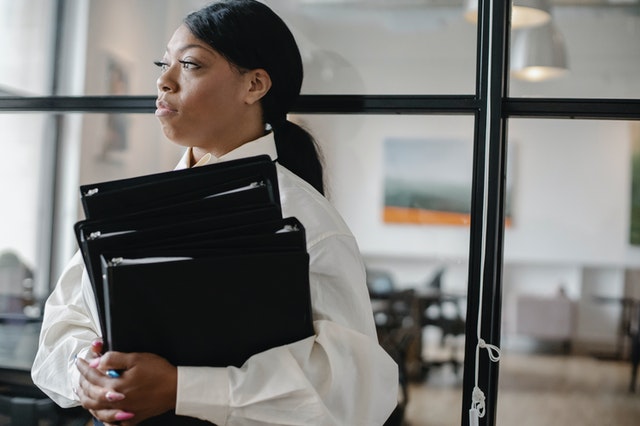 black woman carrying documents in the office