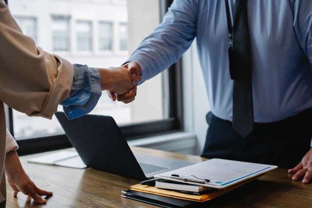 crop colleagues shaking hand in the office