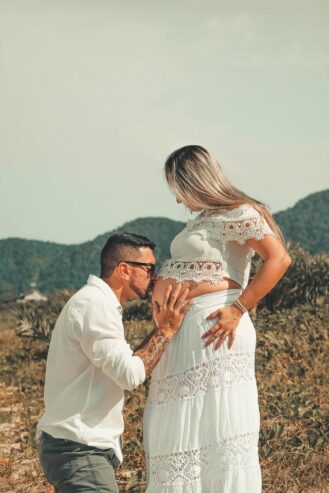 man wearing white dress shirt kissing woman on her baby bump