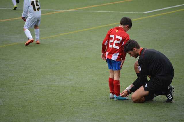 man tying a kid's shoelaces
