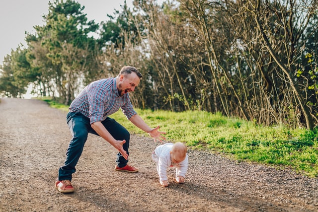 dad watching his child stand up from the ground