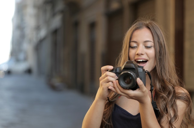woman in black tank top holding a black DSLR