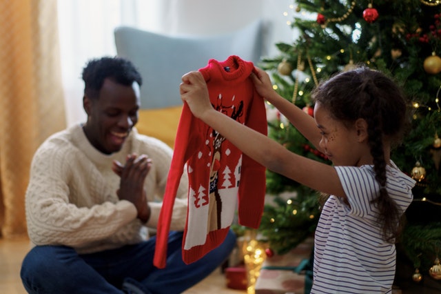 a girl smiling while holding a red christmas sweater