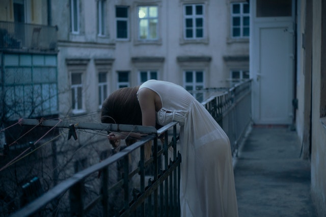 woman leaning on a railing with head down